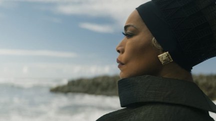 A profile shot of Queen Ramonda (Angela Bassett) staring off into the distance while wearing a black head wrap in a scene from 'Black Panther: Wakanda Forever'