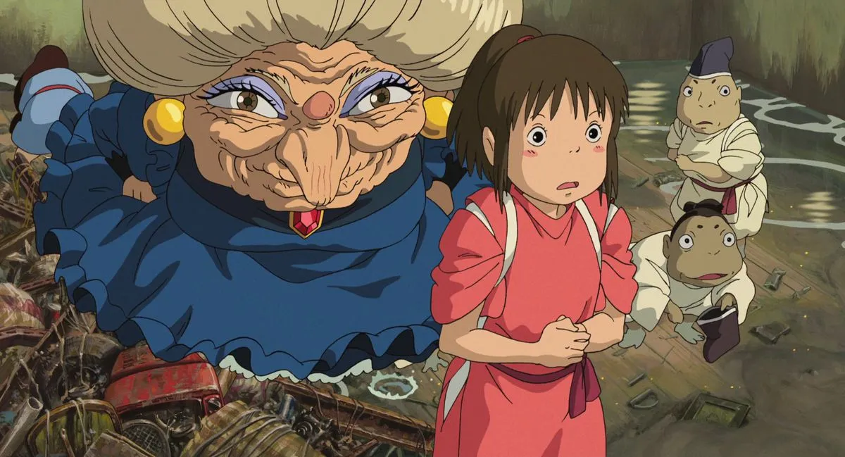 An animated young girl looks nervous as an older woman with a wart on her face stands behind her in "Spirited Away"