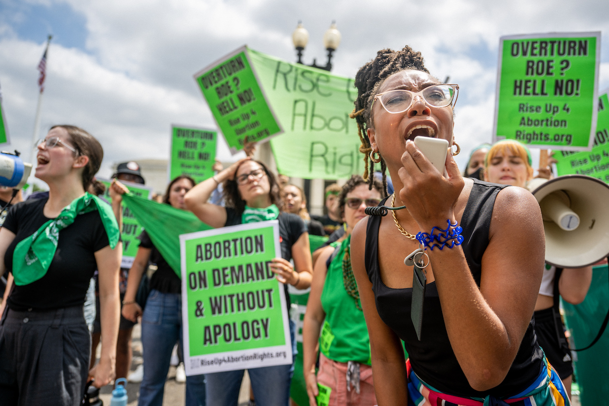 Abortion rights activists protest weating grean and holding green signs.
