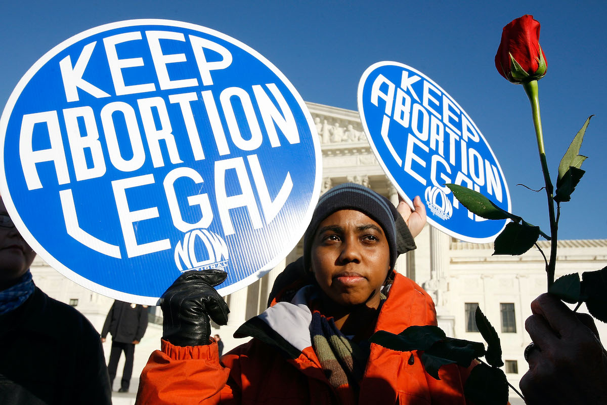 an abortion activist hols a sign reading "keep abortion legal"