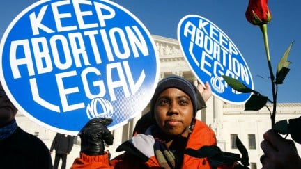 an abortion activist hols a sign reading 