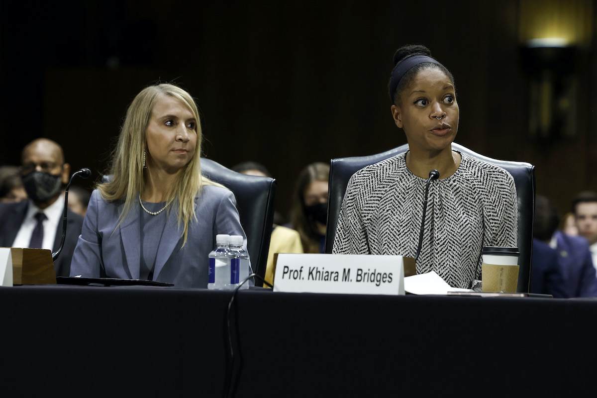 Two witnesses sit at a table in the Senate chamber.
