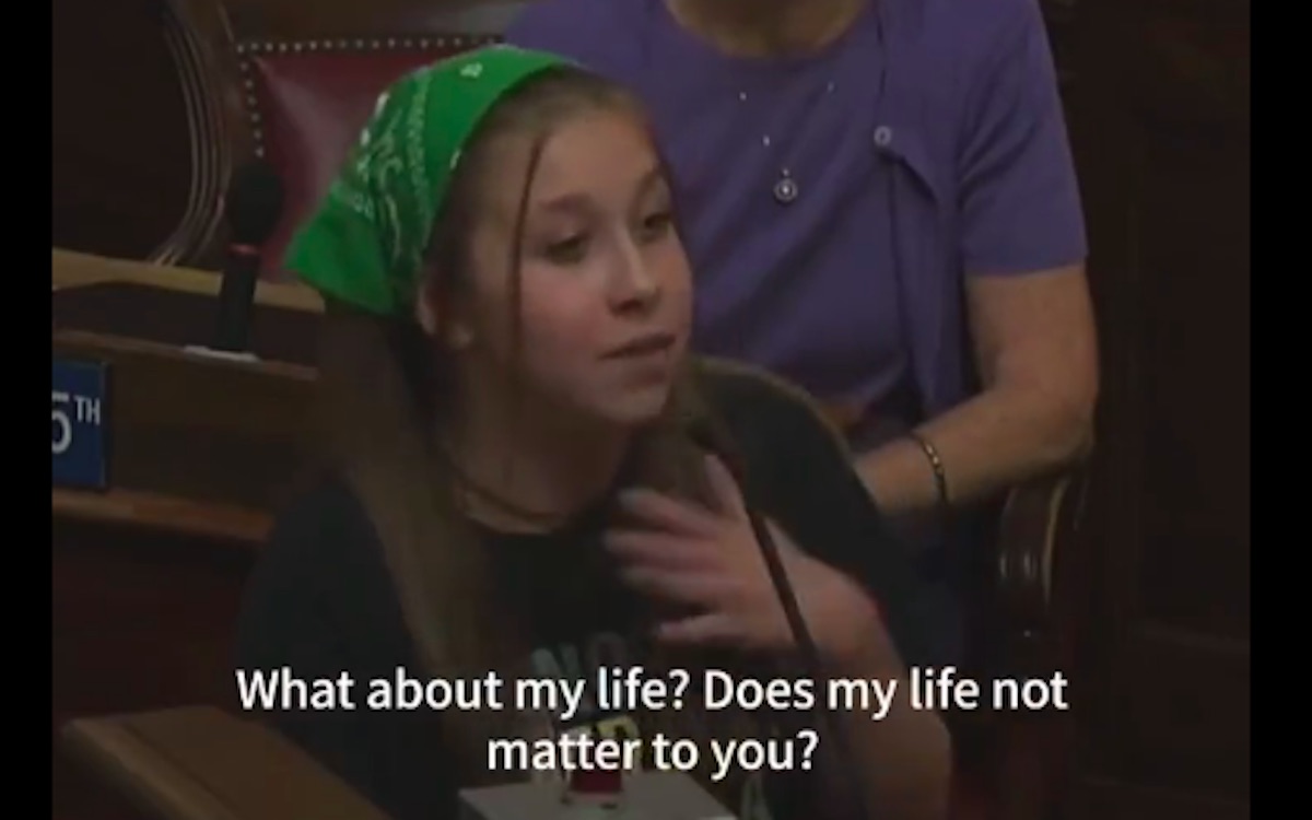 A pre-teen girl wearing a green handkerchief in her hair gestures emphatically with a caption reading "What about my life? Does my life not matter to you?"