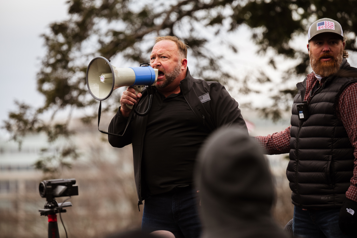 Alex Jones yells into a megaphone from a stage outside