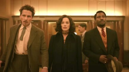 Christian Bale, Margot Robbie, John David Washington dressed in 1930s-era costumes, standing together looking haggard in a scene from Amsterdam.