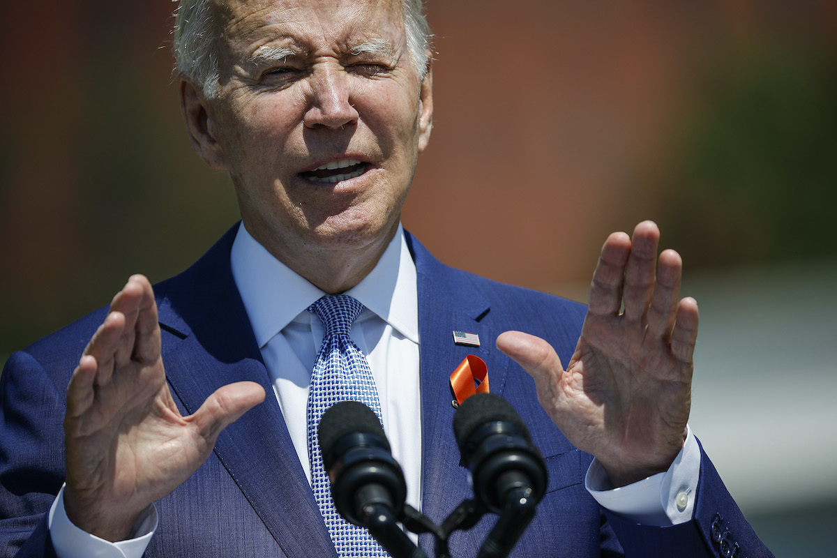 Joe Biden speaks from a podium, holding his hands up with a "wait a minute" gesture