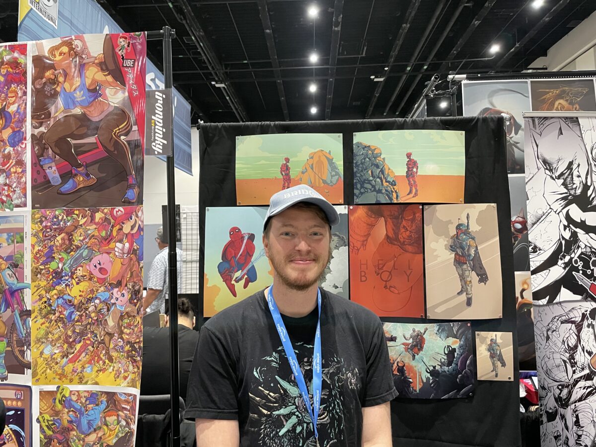 Artist Derek Knierim is smiling from the SDCC booth.