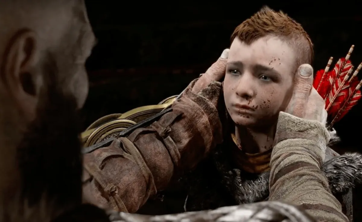 A man holds a young boy's face in his hands in an image from the game God of War