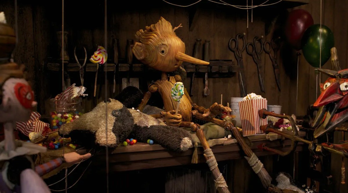 Pinocchio sitting on Gepetto's workbench in Guillermo del Toro's Pinocchio
