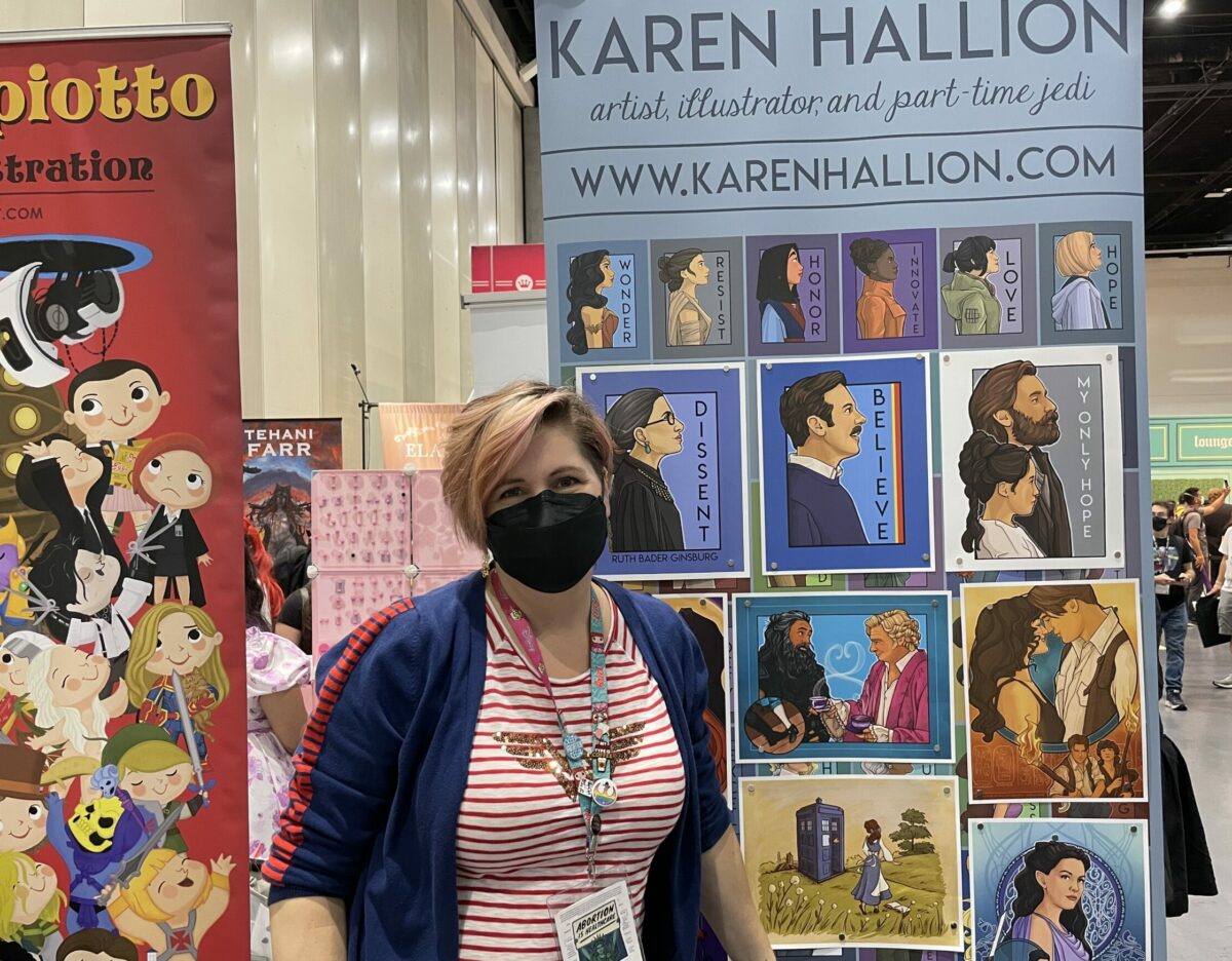 Artist Karen Harion is posing at the SDCC2022 booth.