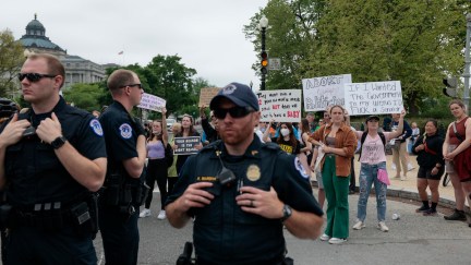 U.S. Capitol police officers stand in front of abortion rights demonstrators outdoors on a public street.