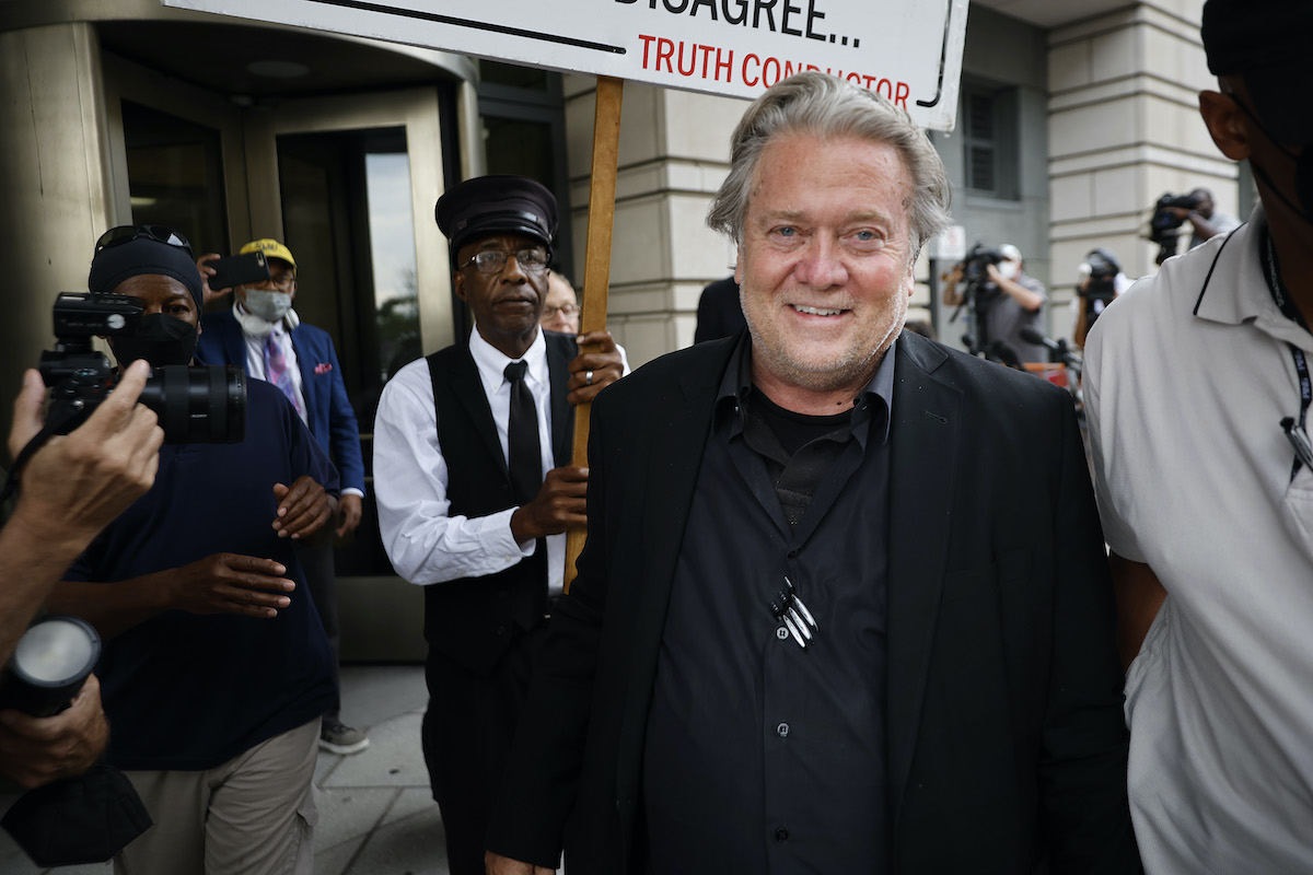 Steve Bannon stands in a small crowd and smiles at the camera.