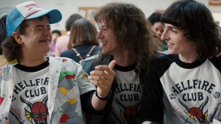 Dustin, Eddie, and Mike laugh in the Hawkins High cafeteria in Stranger Things season 4