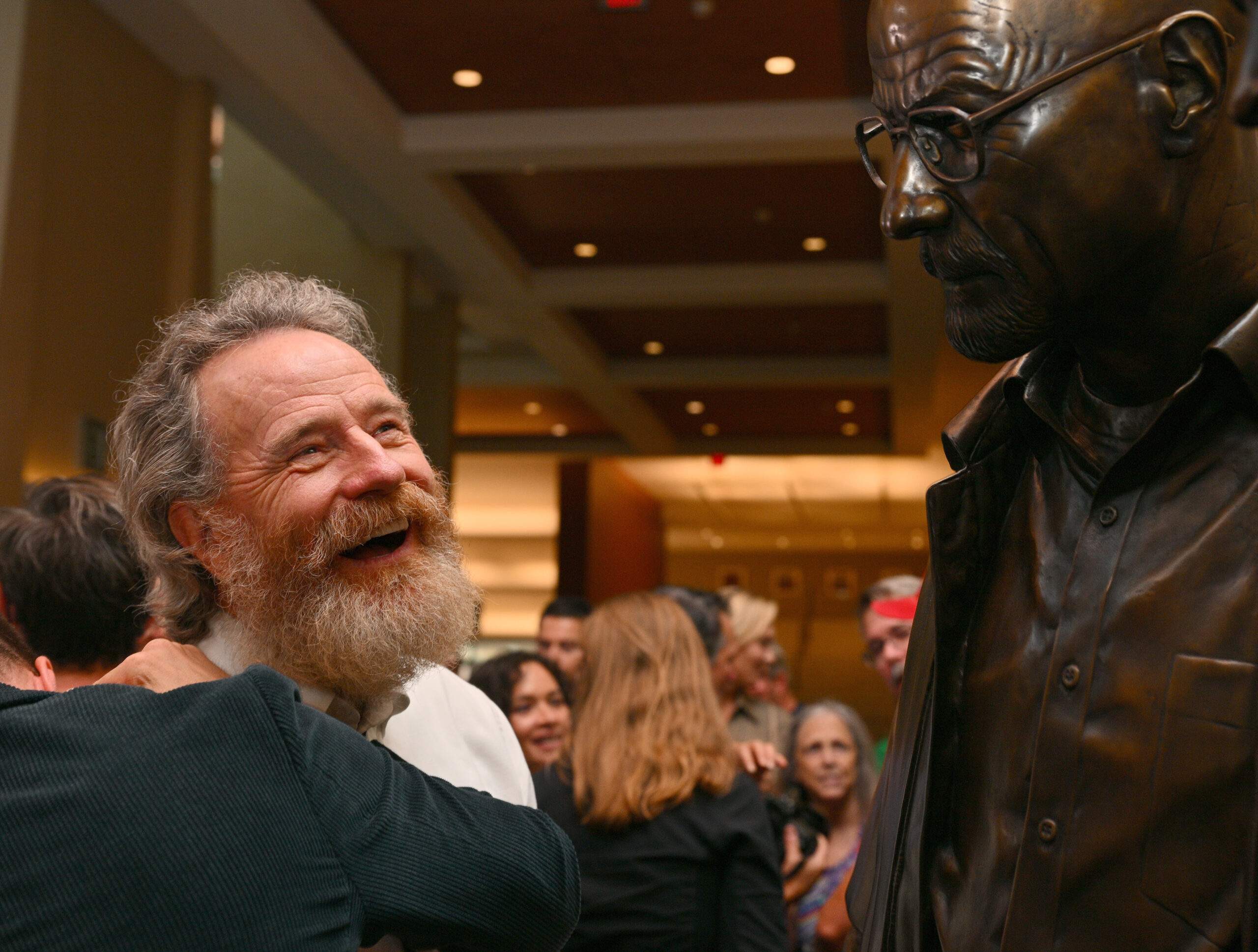 Actor Bryan Cranston reacts while looking at a bronze statue depicting television character Walter White, played by Cranston from the series "Breaking Bad" at the Albuquerque Convention Center on July 29, 2022 in Albuquerque, New Mexico.