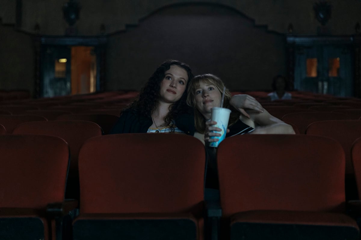 KJ, played by Delia Cunningham, and her girlfriend Lauren, played by Maren Lord, watching a movie in a theater 