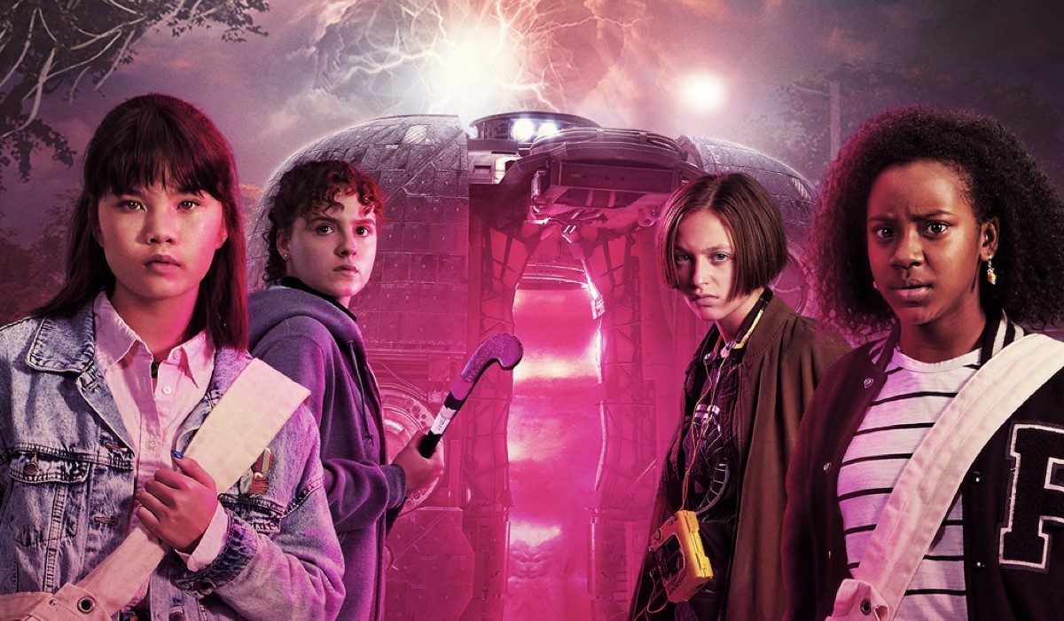 Official artwork for Paper Girls featuring Erin, KJ, Mac, and Tiff standing in front of a time travel vessel