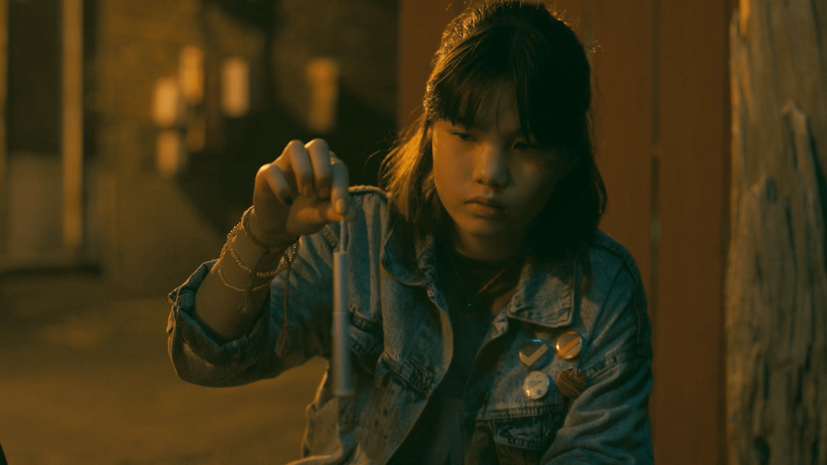 Erin, played by Riley Lai Nelet, looking a tampon that she is dangling by its string