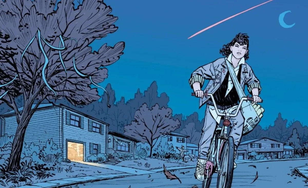 An illustration by Paper Girls creator Cliff Chiang of Erin Tieng riding her bicycle along her paper route with a shooting star in the sky behind her