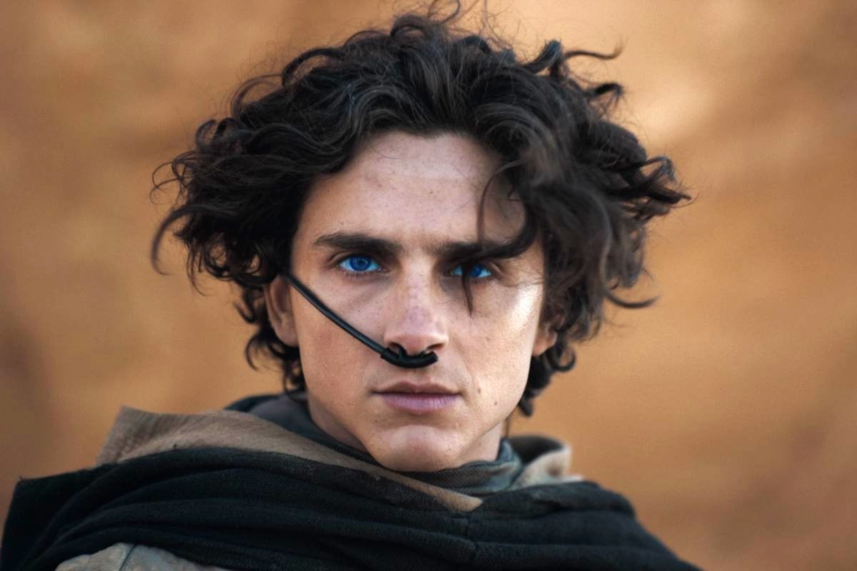 Timothée Chalamet as Paul Atreides with glowing blue eyes and wind swept hair in 'Dune Part 2.'