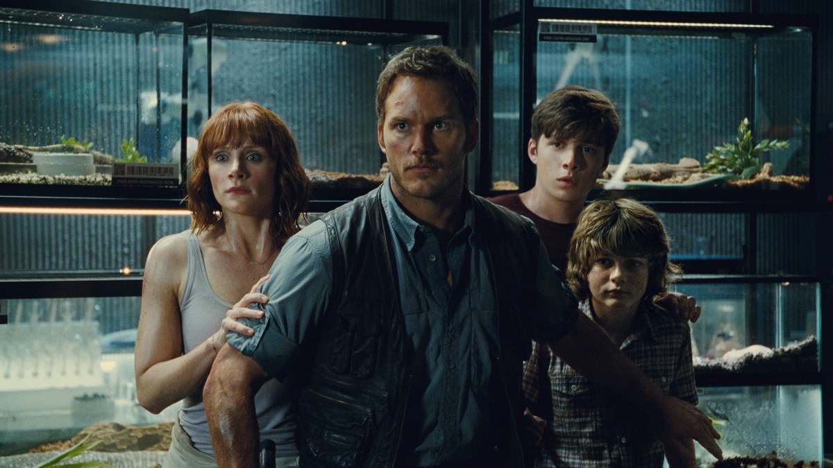 Chris Part stands guard in front of three people in Jurassic World