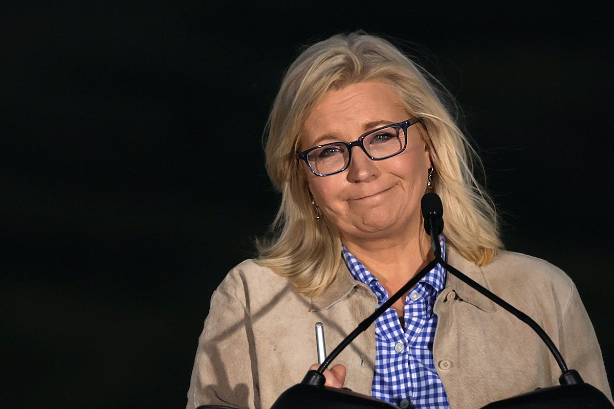 Liz Cheney gives an unhappy, tight-lipped smile from a podium during her concession speech.