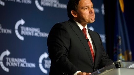 Ron DeSantis makes a face speaking from a podium at a Turning Point rally.