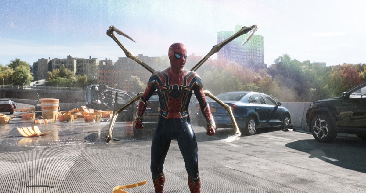 Spider Man stands on a rooftop with his robotic spider legs outstretched in "Spiderman: No Way Home" 
