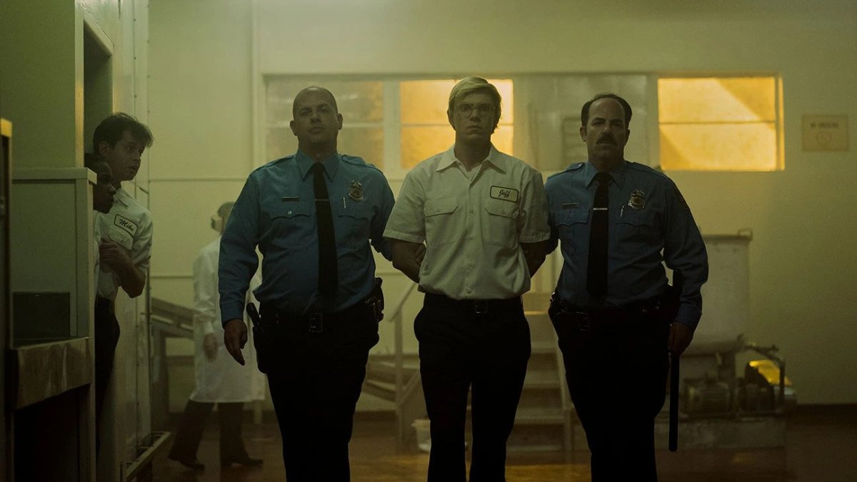 Evan Peters as Jeffrey Dahmer flanked by officers in Monster: The Jeffrey Dahmer Story