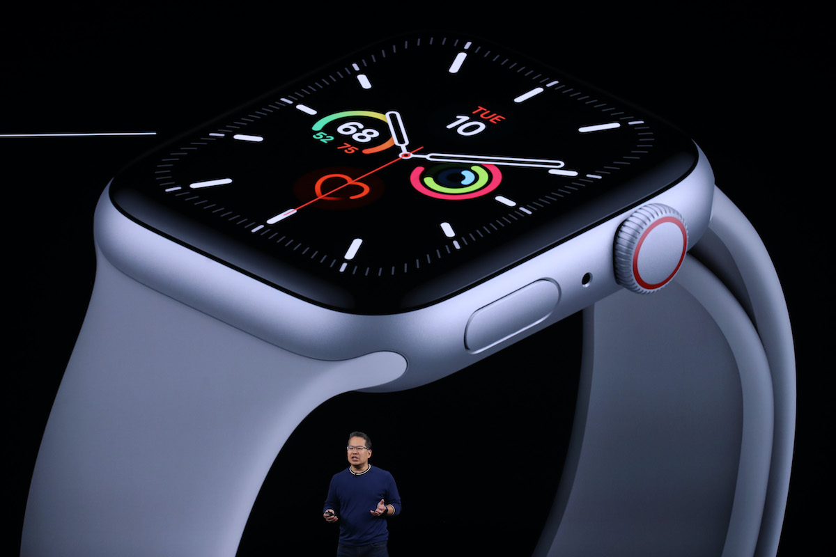 A man (Stan Ng) looks very small in the foreground in front a giant projection of an Apple Watch behind him.