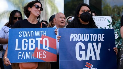 A group of demonstrators hold pro-LGBTQIA signs