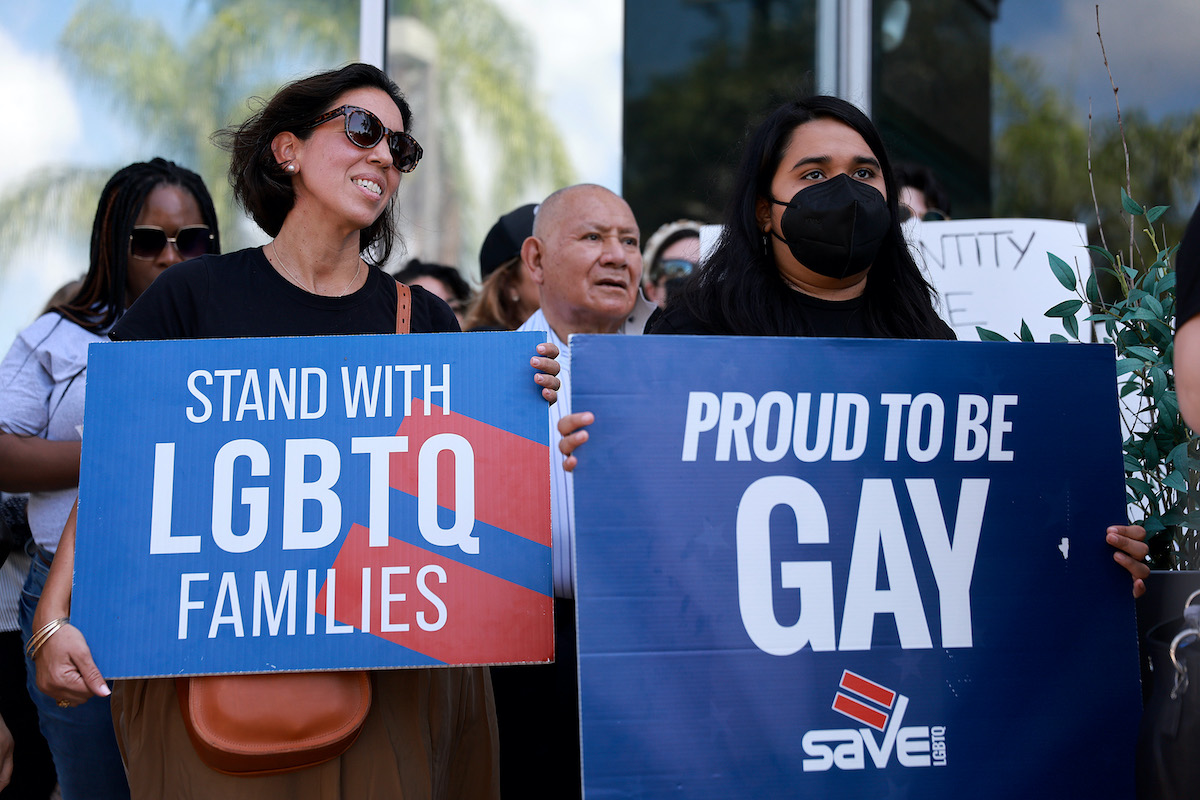 A group of demonstrators hold pro-LGBTQIA signs