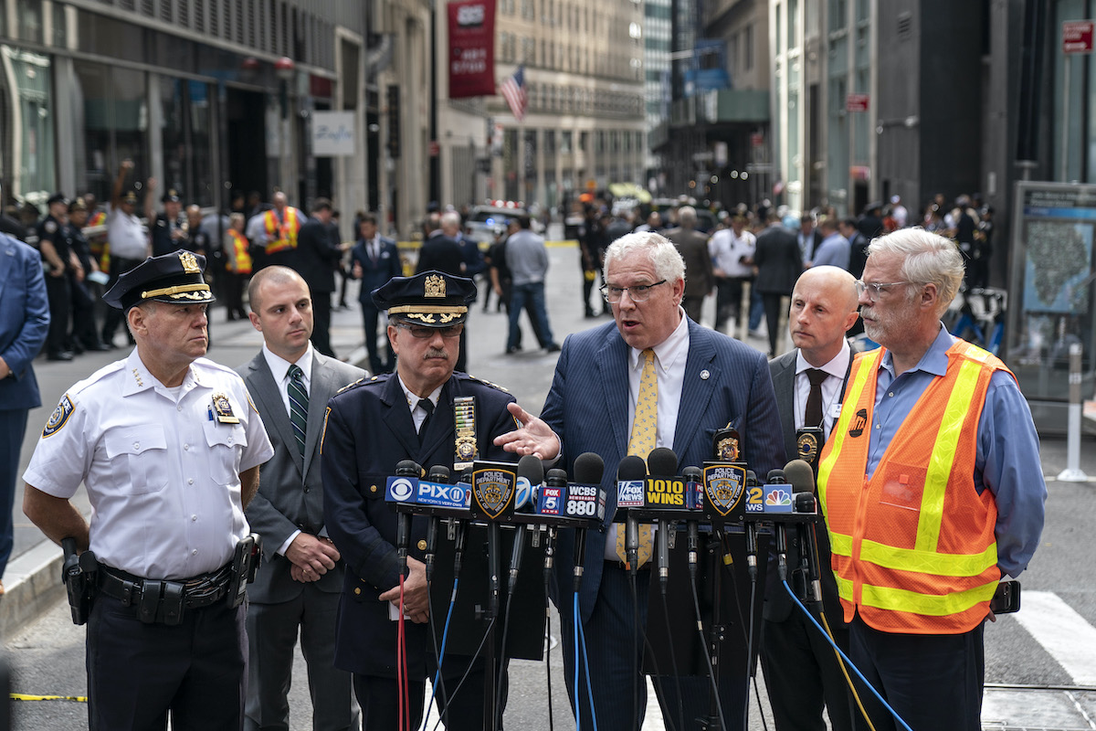 A group of older white men, some in police uniforms, speak during a press conference from a New York City street.