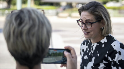 Kyrsten Sinema makes a face during an interview with someone filming her on a cell phone.
