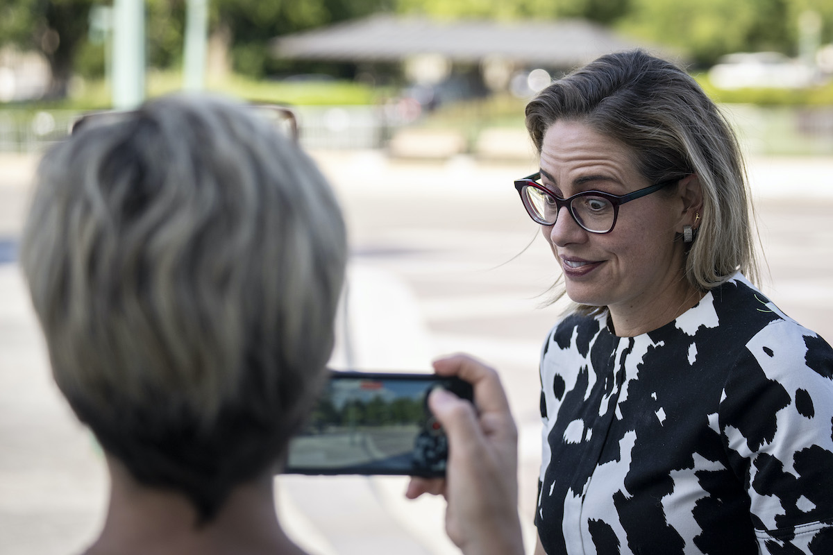 Kyrsten Sinema makes a face during an interview with someone filming her on a cell phone.
