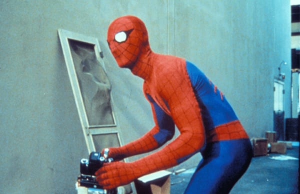 Spider-Man leans over his camera.