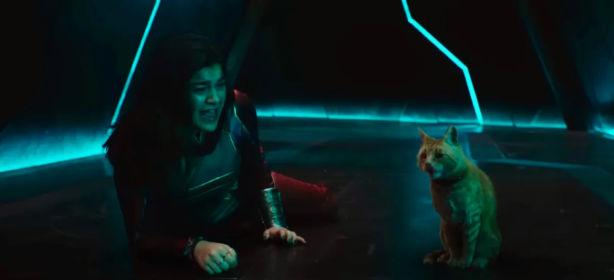 Kamala Khan lies on the floor of a dark hallway, screaming in fear at an orange tabby cat.