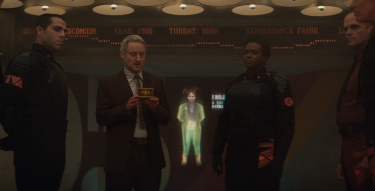 Loki looks at a hologram of a variant of himself, wearing sunglasses.