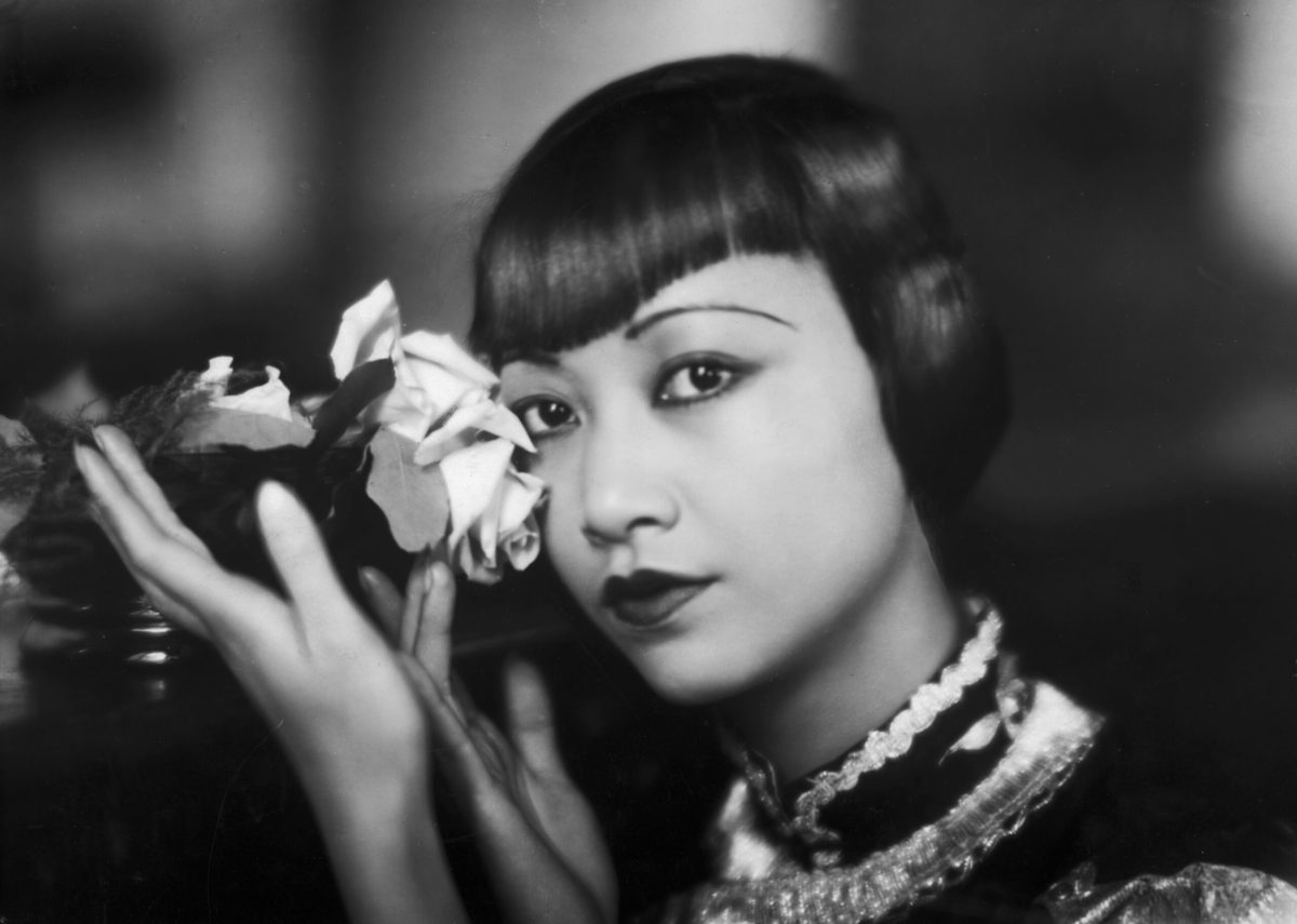 circa 1935: American film star, Anna May Wong (1905 - 1961) poses with a cut rose.