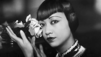 circa 1935: American film star, Anna May Wong (1905 - 1961) poses with a cut rose.