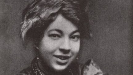 Photograph of Pamela Colman Smith, wearing a scarf in her hair and a mischievous smile.