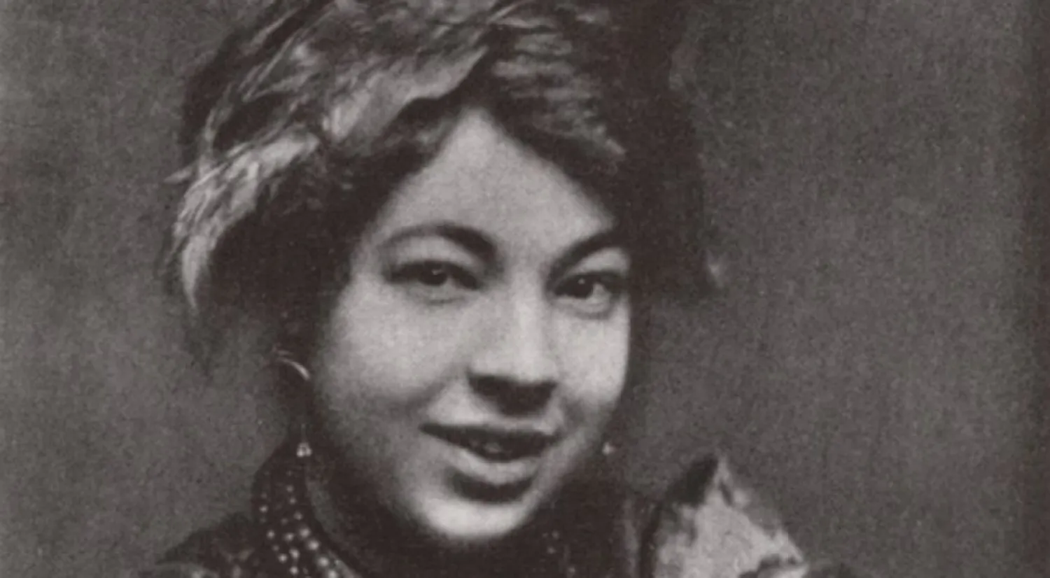 Photograph of Pamela Colman Smith, wearing a scarf in her hair and a mischievous smile.