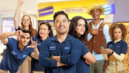 The cast of 'Blockbuster' poses as a group in from of a Blockbuster store backdrop.