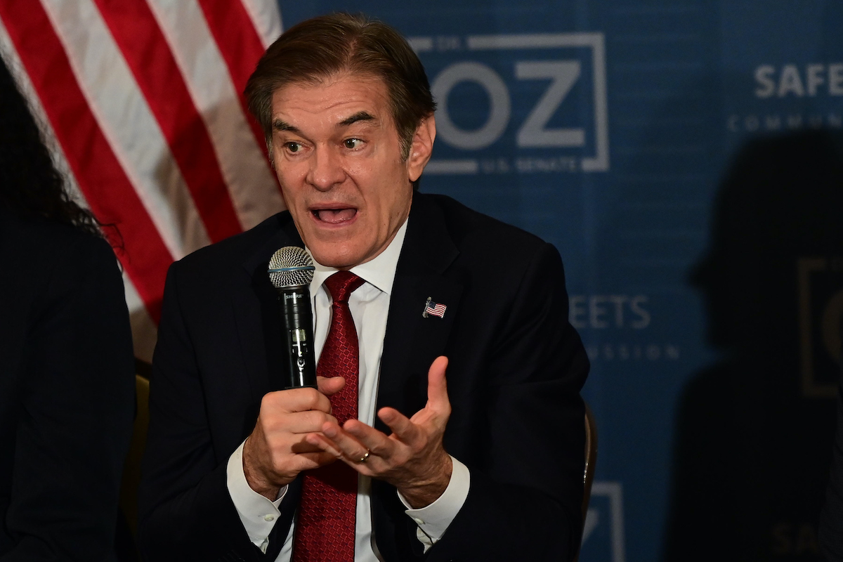 Dr. Oz looks flustered while speaking into a microphone at a campaign event.