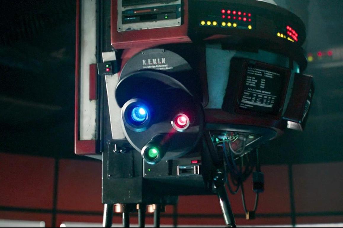 K.e.v.i.n. is a robotic droid, with various features such as buttons, lights, and AI equipment.