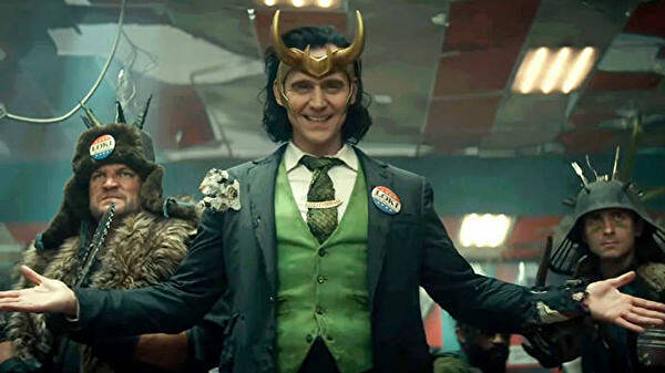 President Loki smiles with his henchmen behind him.
