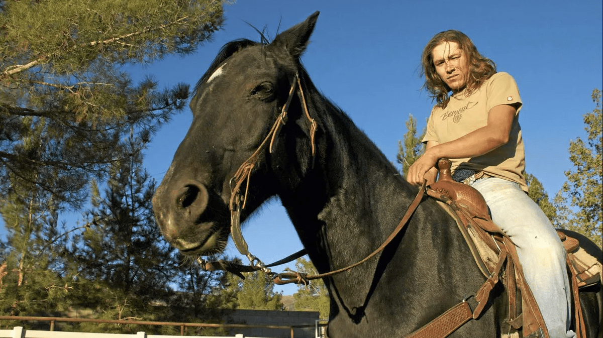 A modern Native American man sits on top of a horse in a still from the documentary 'Reel Injun'