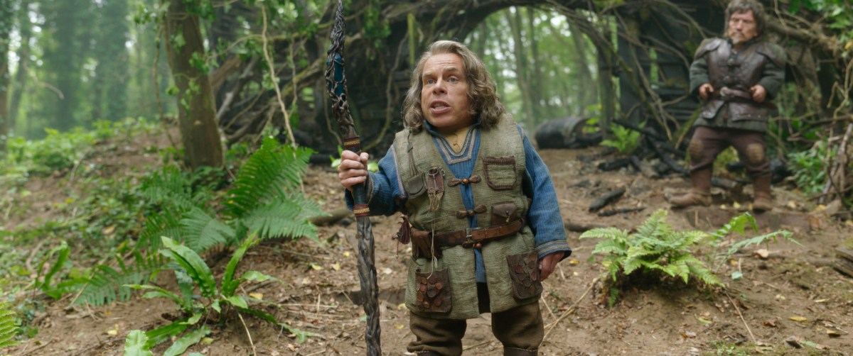 Willow (Warwick Davis) stands in the woods with a staff.