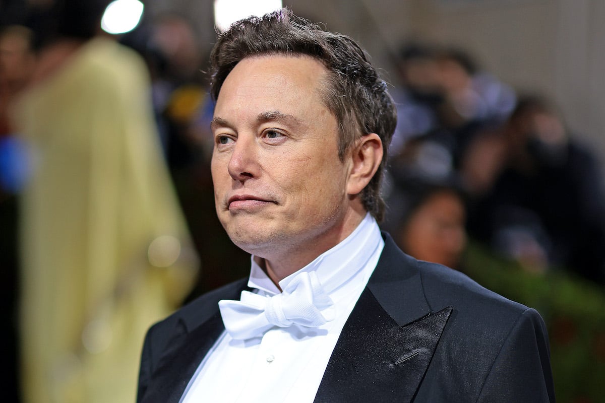 Elon Musk frowns slightly wearing a tux on a red carpet.