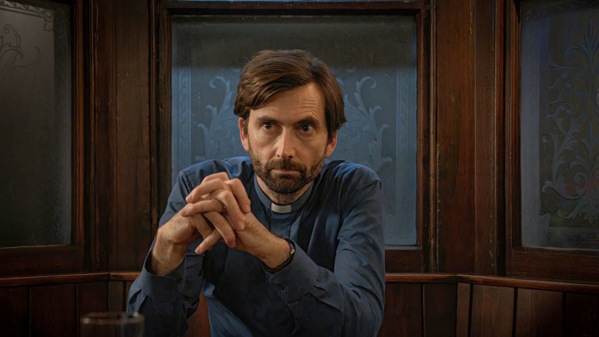 Harry Watling (David Tennant) sits pensively at a table.