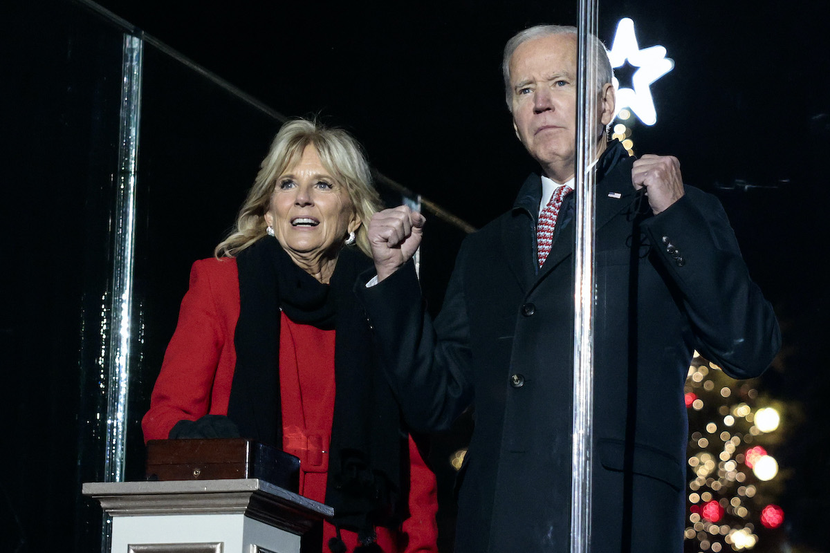 Jill and Joe Biden look intenseley in front of them with a large Christmas tree in the background.